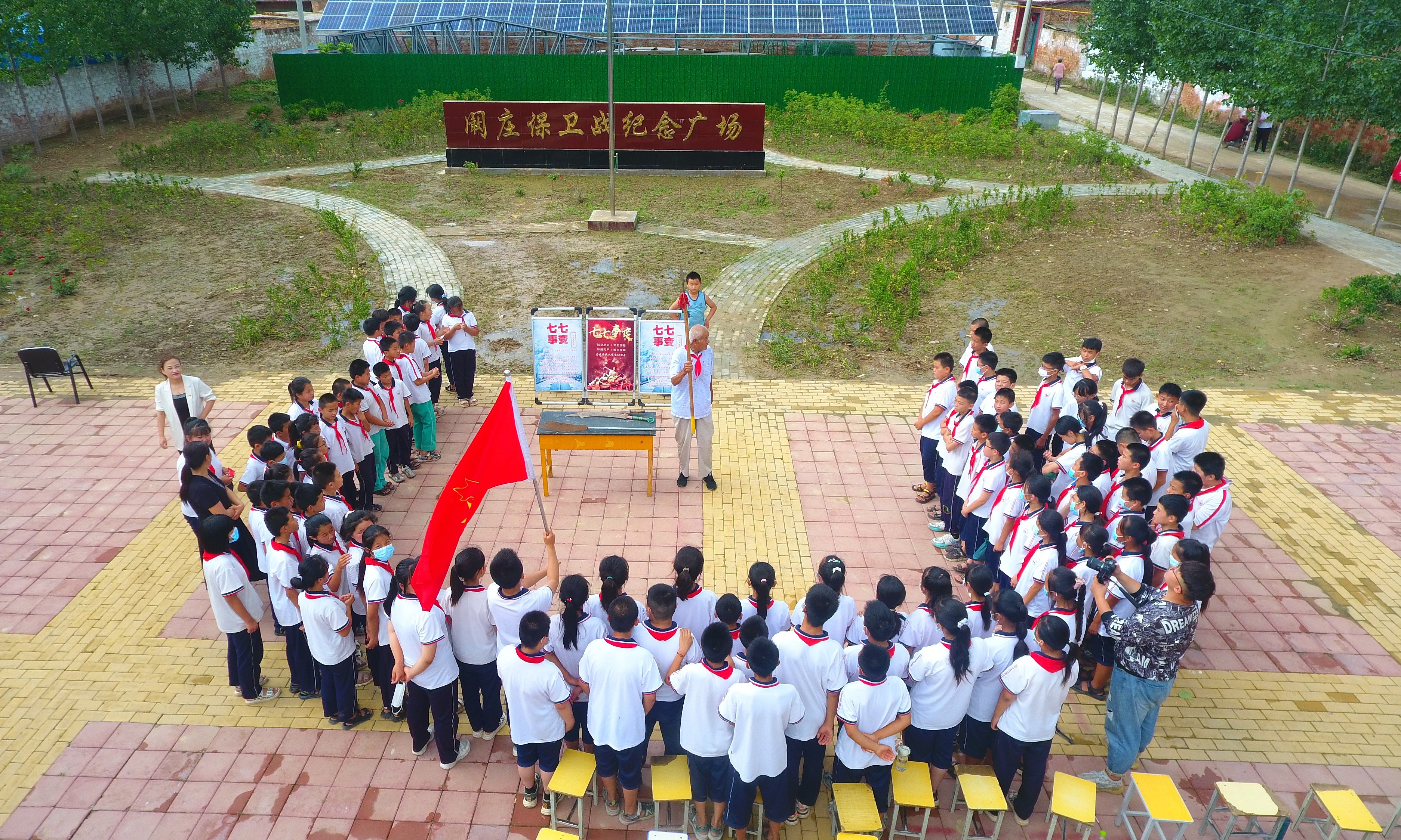 2022年7月6日，山東省聊城市，在茌平區(qū)菜屯鎮(zhèn)闞莊村的闞莊保衛(wèi)戰(zhàn)紀念廣場，闞莊保衛(wèi)戰(zhàn)親歷者王光木老人，為小學(xué)生們講述抗戰(zhàn)故事，展示大刀、長矛。